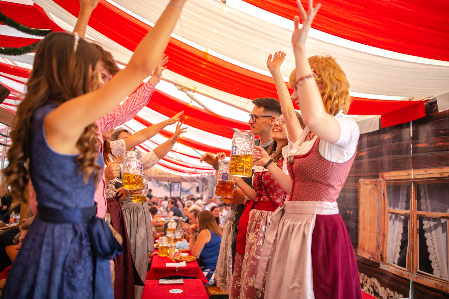 Besucher stehen im Bierzelt auf der Bank und feiern 